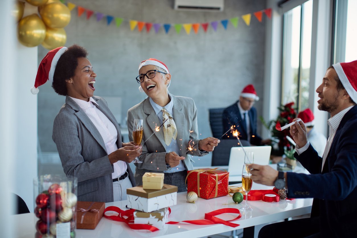 Group business colleagues having fun at a Christmas party in the office wearing Santa hats.