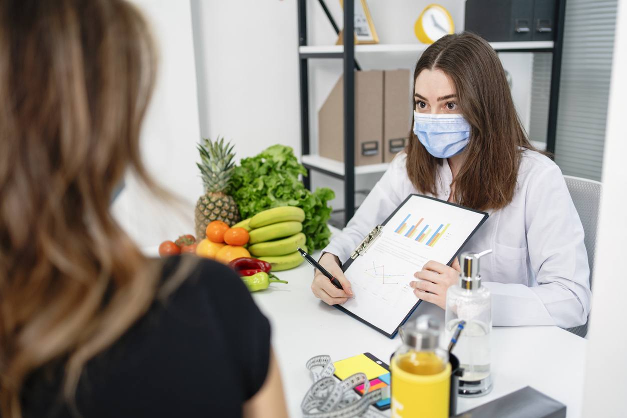 A female dietitian holding a diet plan during a consultation with a patient in the office.