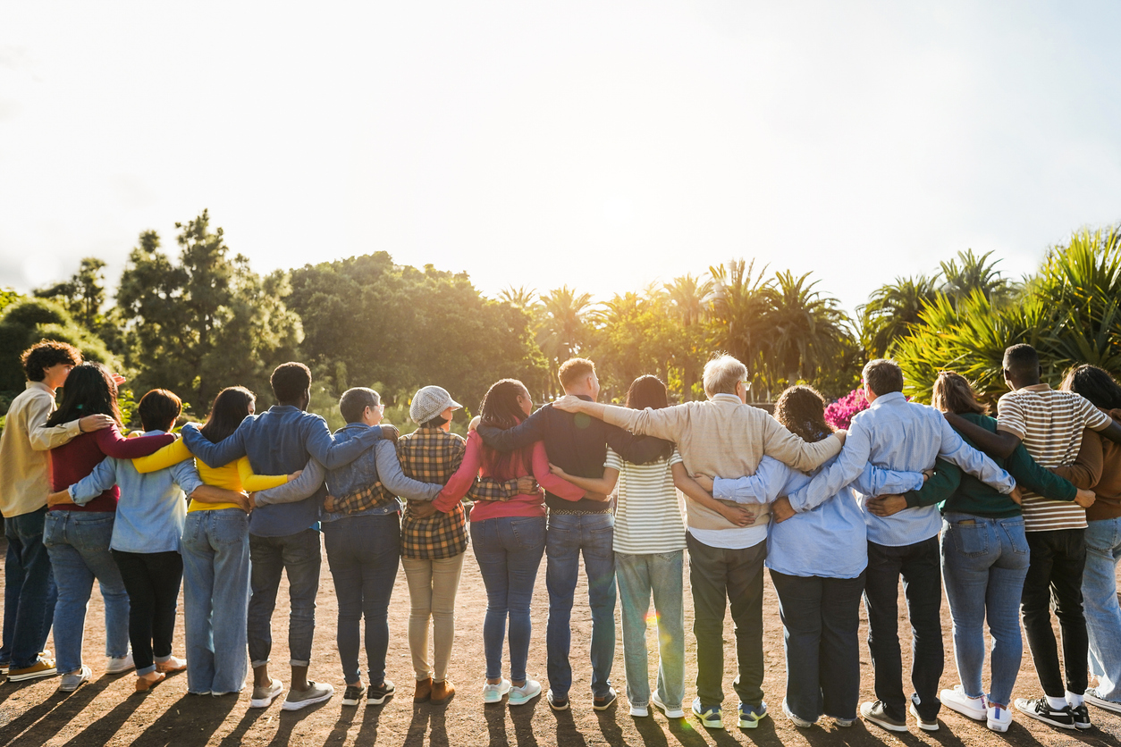 An image of a line of people standing outside linked together with their arms in a gesture of mutual support.