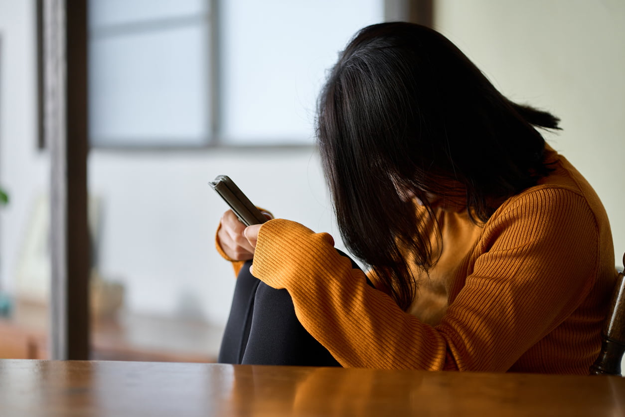 A distressed woman hiding her face and holding her knees.