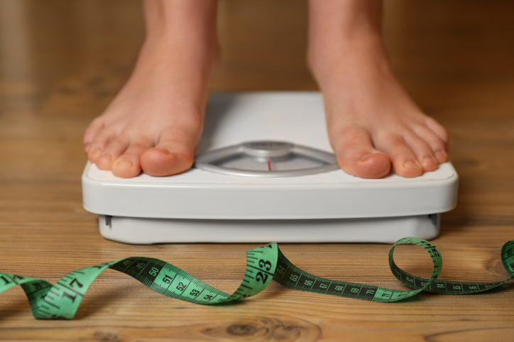 A pair of feet on a scale belonging to a person who wants to maintain weight loss after LAP-Band surgery.