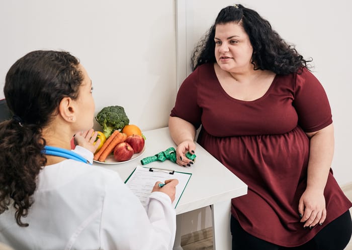 A female surgeon discusses potential complications from weight loss surgery with her female patient.