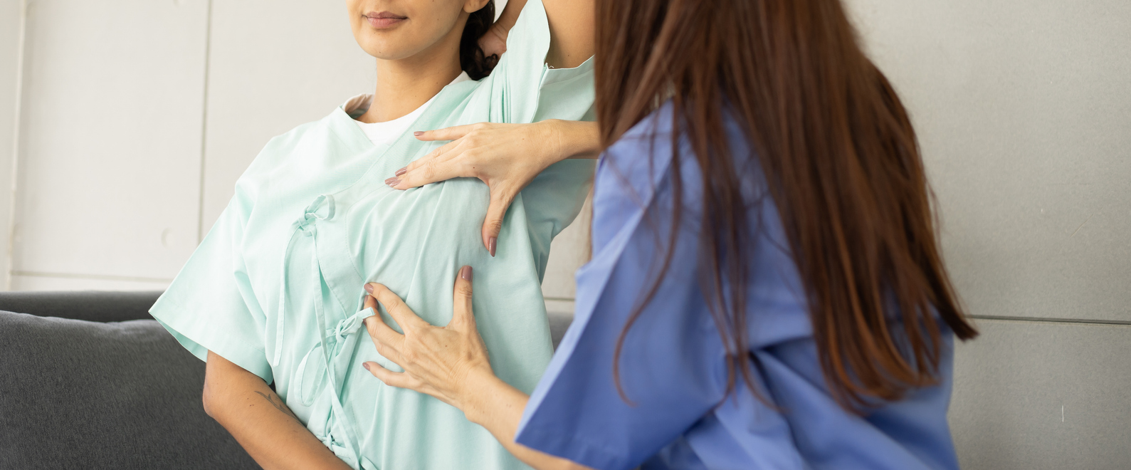 A doctor in scrubs checks a patient’s left breast before her minimally invasive breast cancer surgery.