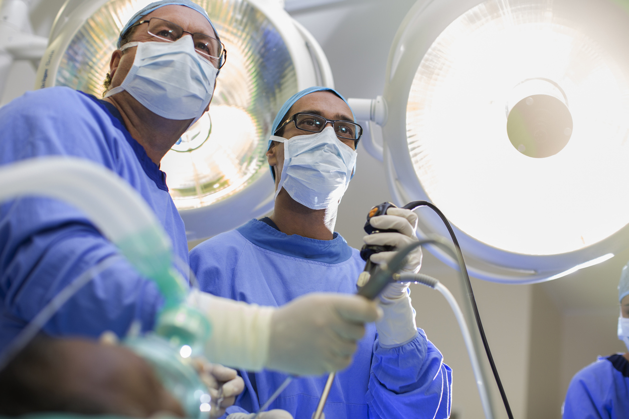 A pair of doctors in scrubs working with a laparoscopic camera for precise treatment during minimally invasive surgery. 